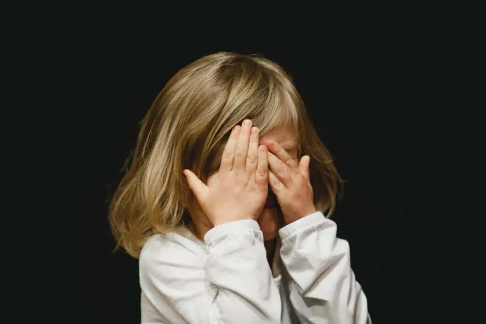 Child with hands in front of her face
